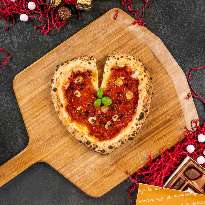 Heart shaped pizza on a wooden pizza peel