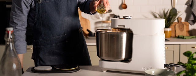 person adding oil into halo pro spiral dough mixer in modern kitchen.