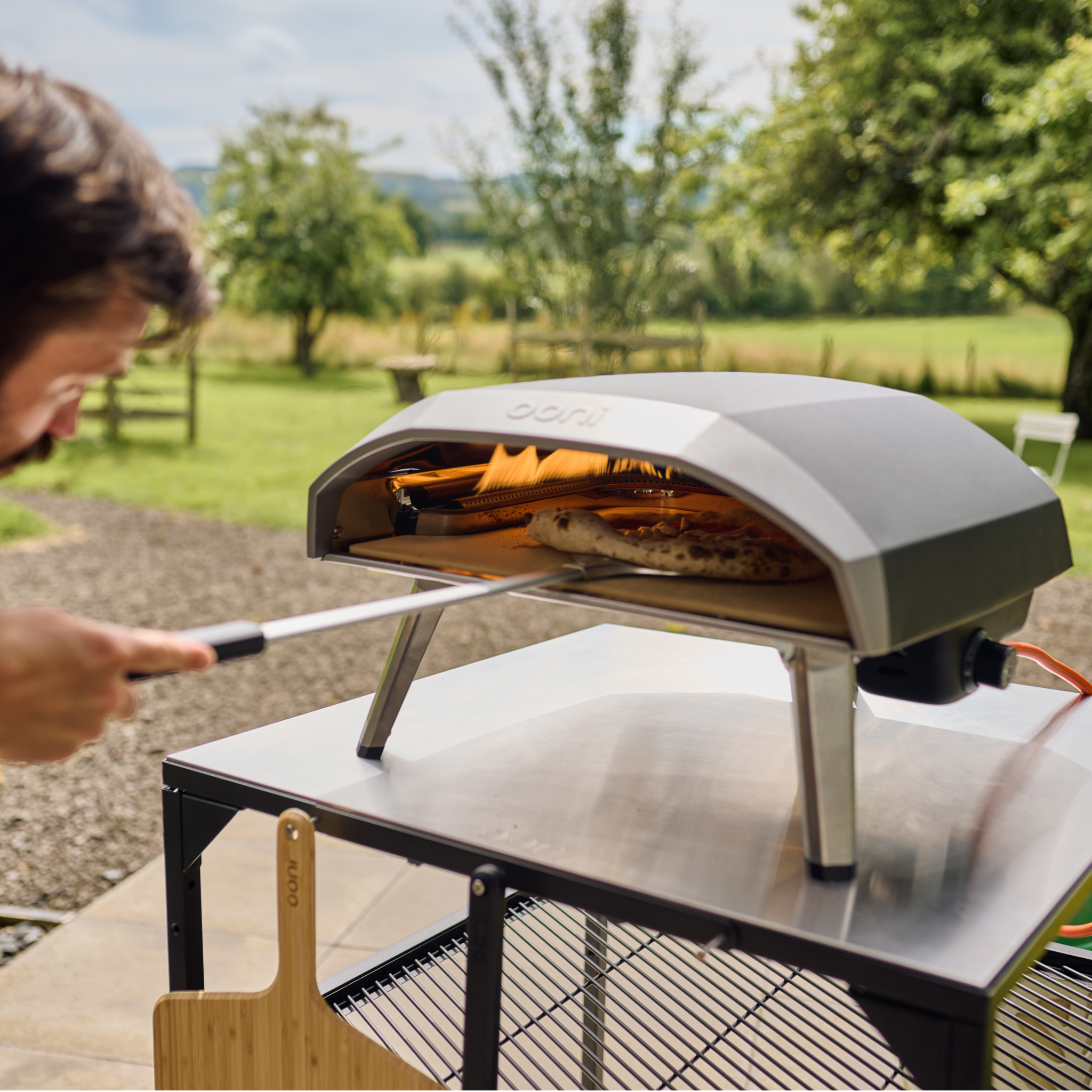 person using the ooni pizza turning peel to turn pizza inside of the Ooni koda 16 Gas Powered Pizza oven