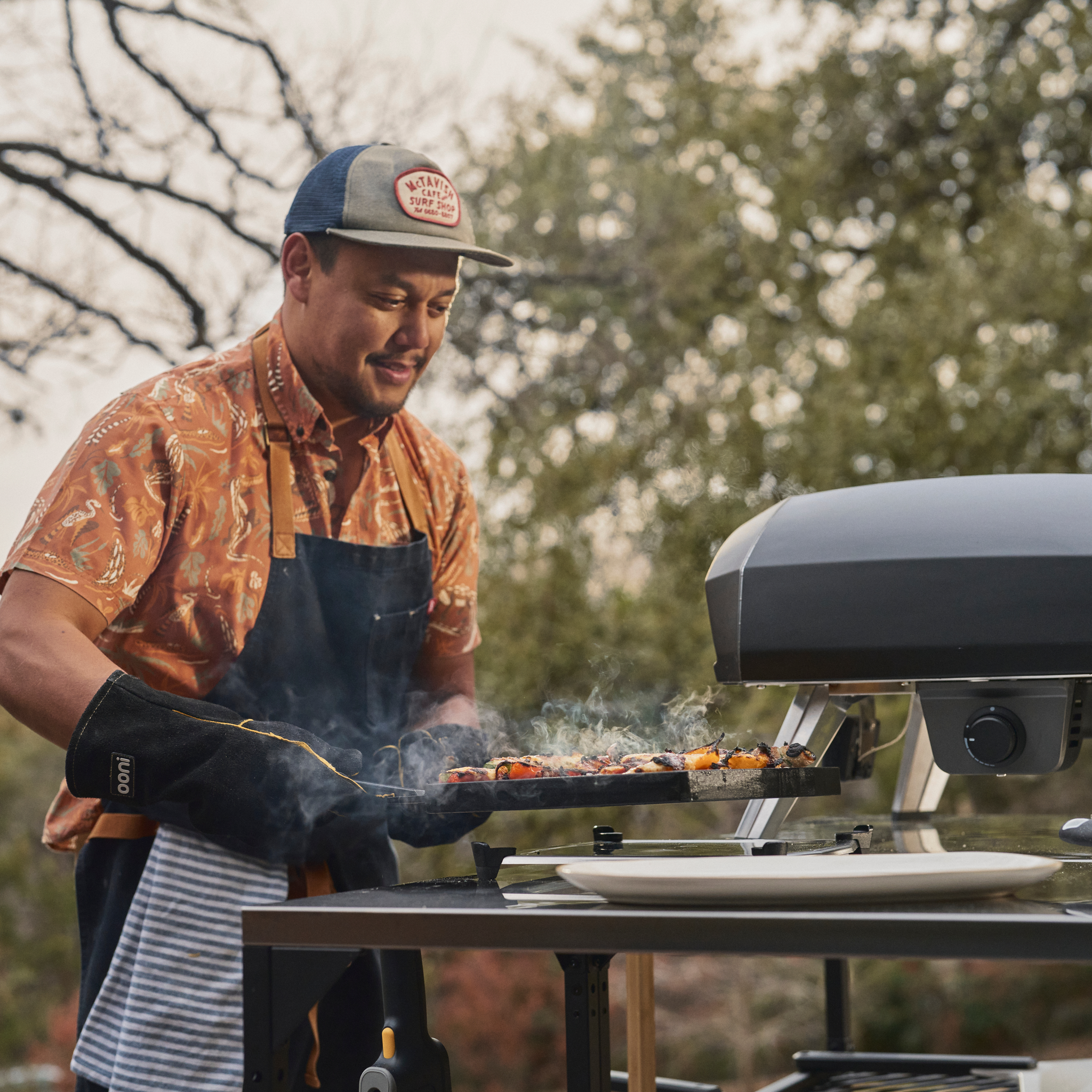 person removing a dual sided grizzler pan from the ooni koda 2 pro. 