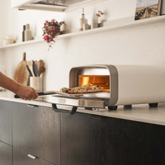 Person taking a pizza out of the Polar White Volt 2 Electric Pizza Oven.