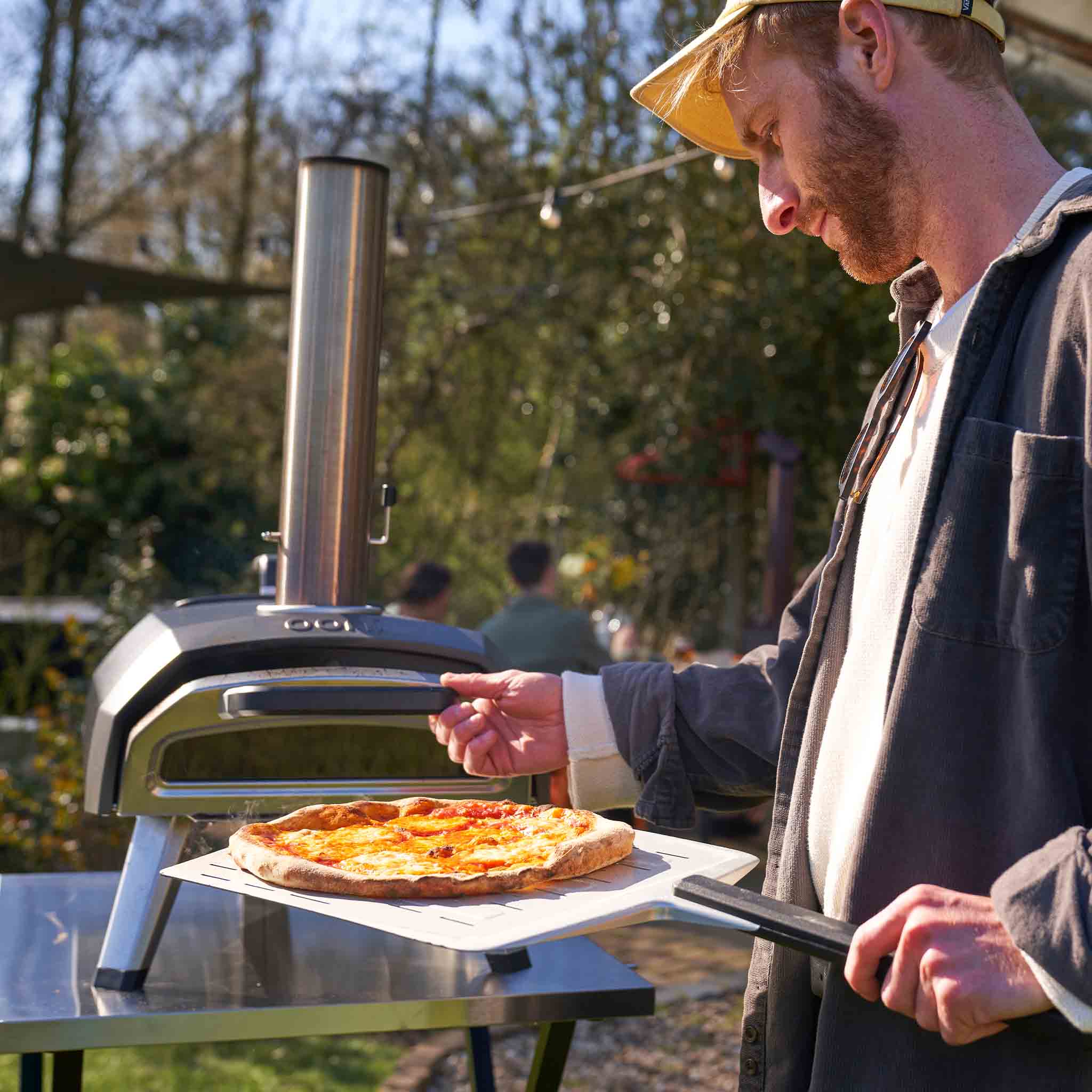 person removing a pizza from the Ooni Karu 2 multi-fuel pizza oven 